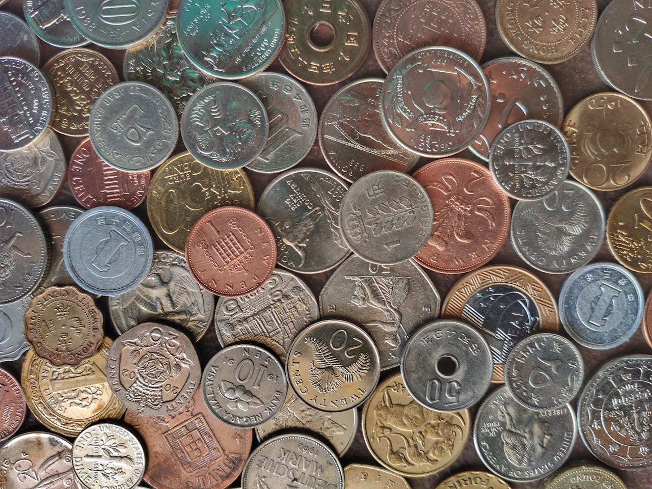 hero-img-02 Diverse collection of world coins in a flat lay arrangement, showcasing different currencies and designs.