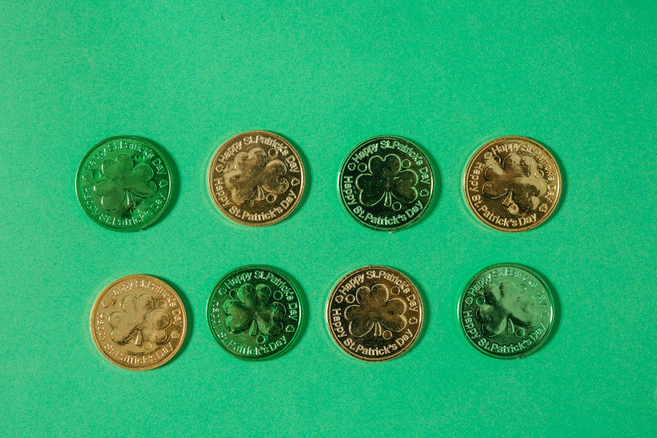 services-01 Top view of gold coins with clover pattern arranged in rows on light green surface